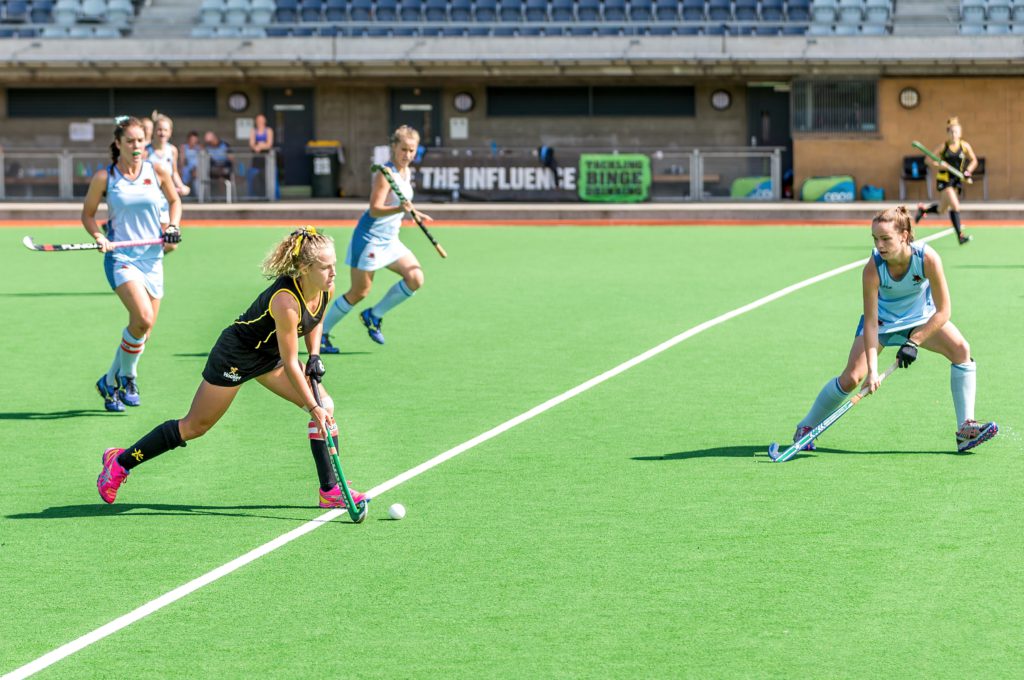 women playing a hockey game on an artificial grass pitch