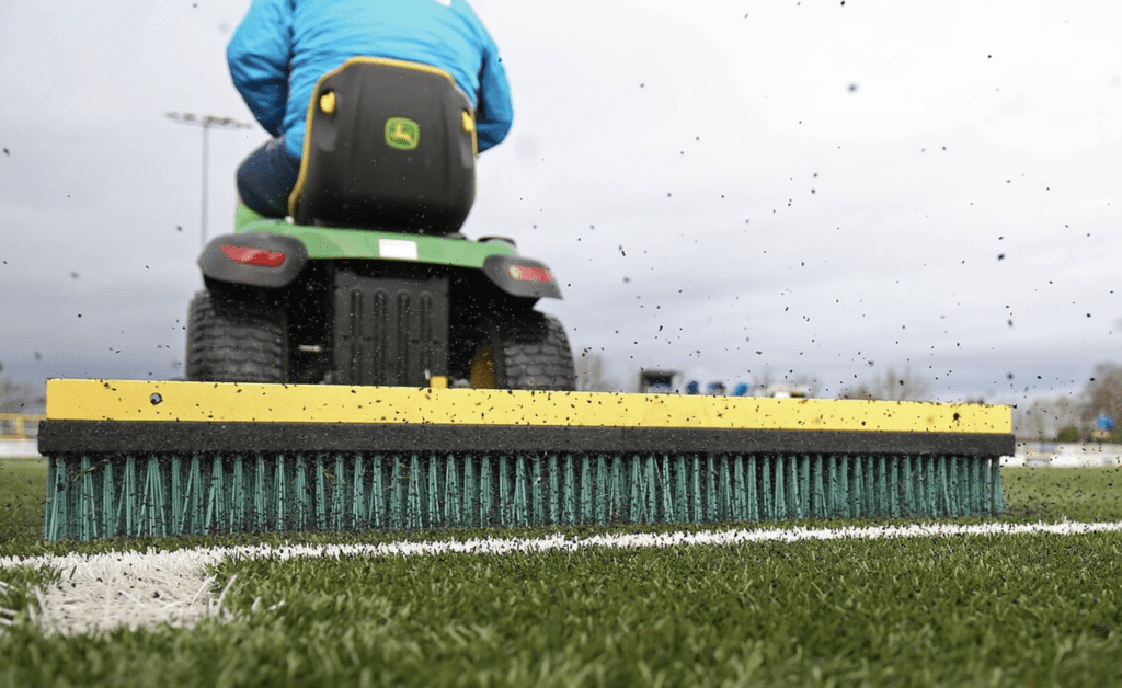 tractor brushing a 3g football pitch as part of regular maintenance